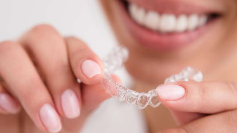 Invisalign Dedham | patient holding clear aligner